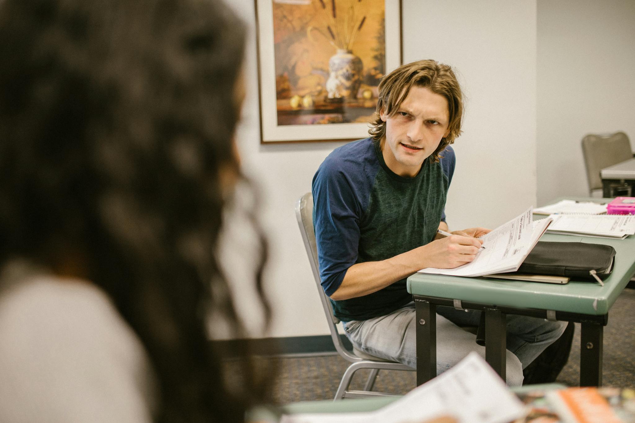 Students engaging in discussion during an exam in a classroom, conveying themes of education and collaboration.